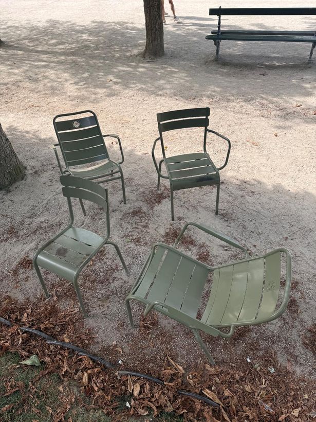 Four chairs pulled into a loose circle under a tree in Luxembourg Gardens.